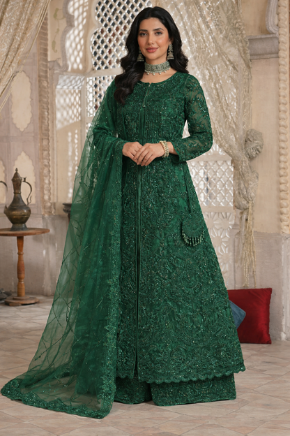 Woman in a green embroidered traditional outfit standing in a decorative room.