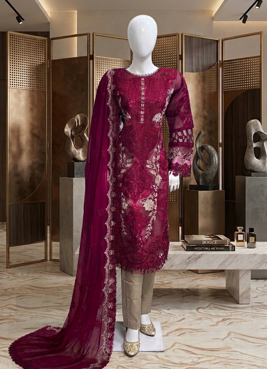 Mannequin wearing a burgundy embroidered dress with a long train in an elegant room.